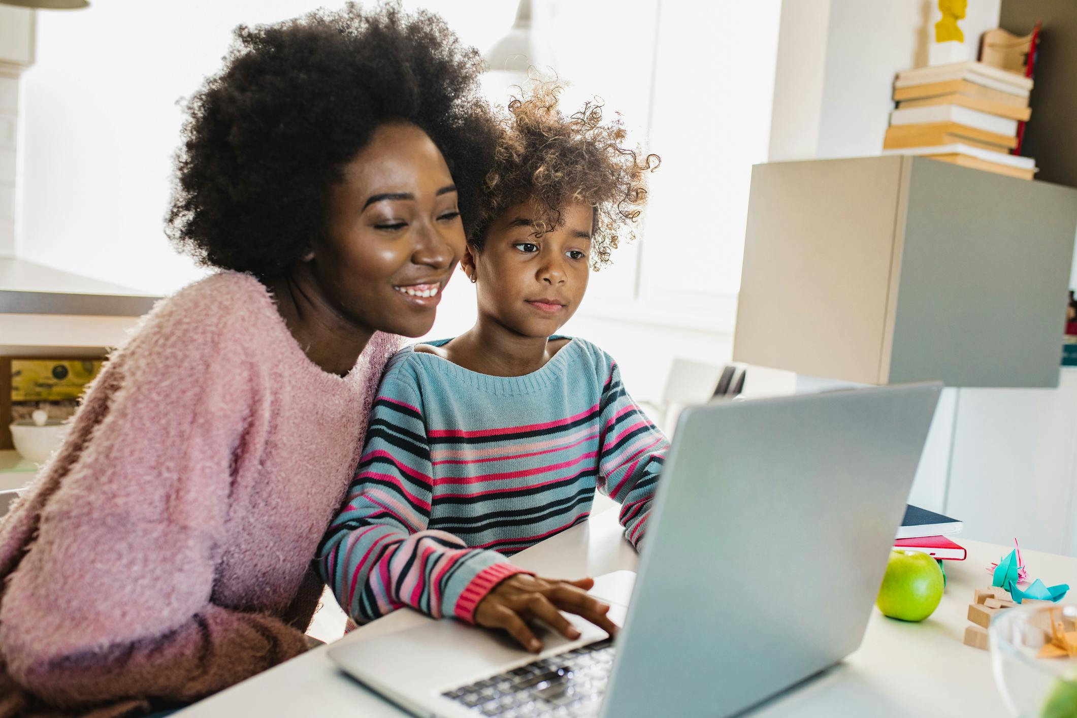 A mother and daughter sitting at a laptop together