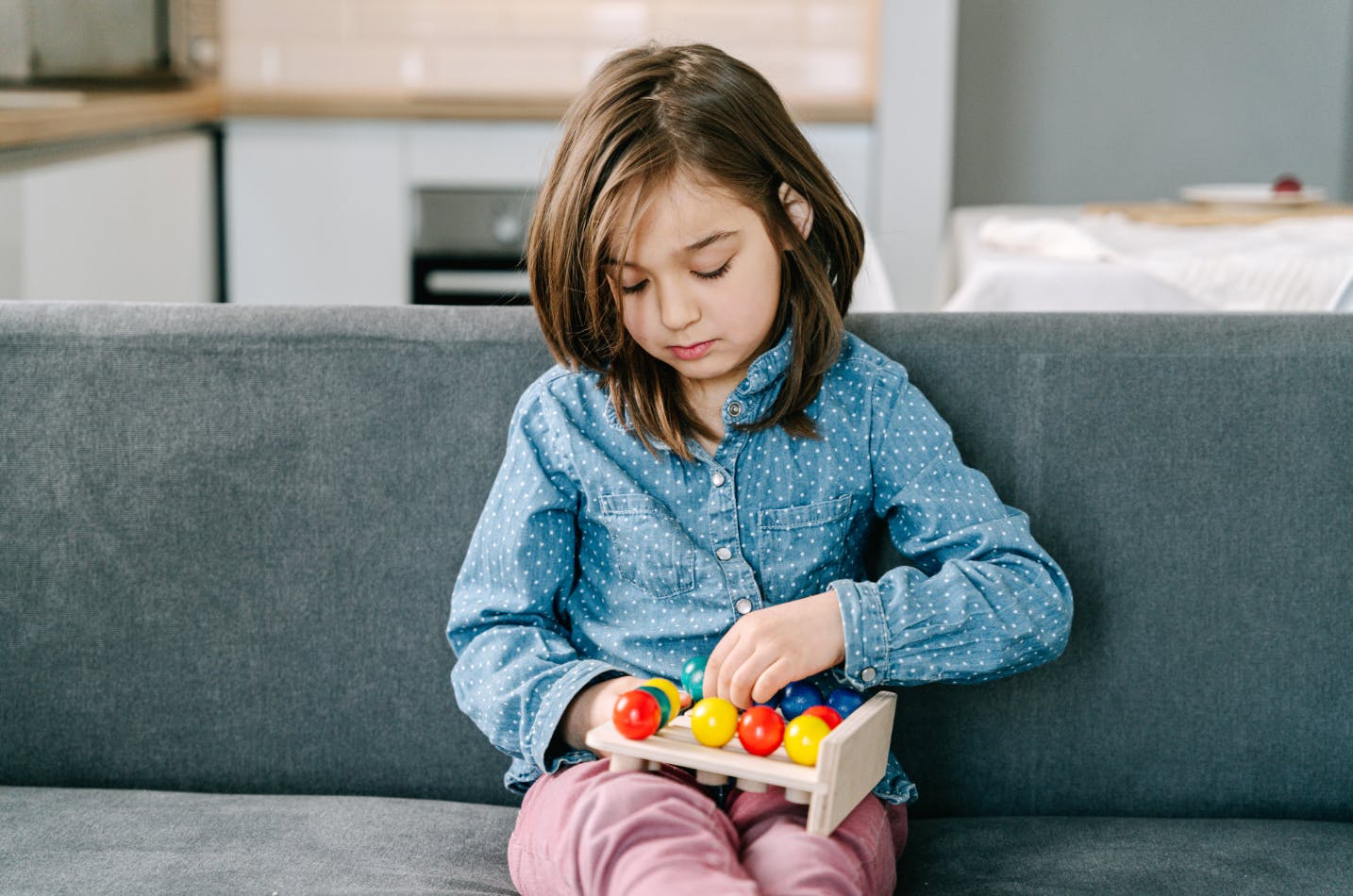 Bored child playing with a toy on the couch to avoid doing schoolwork