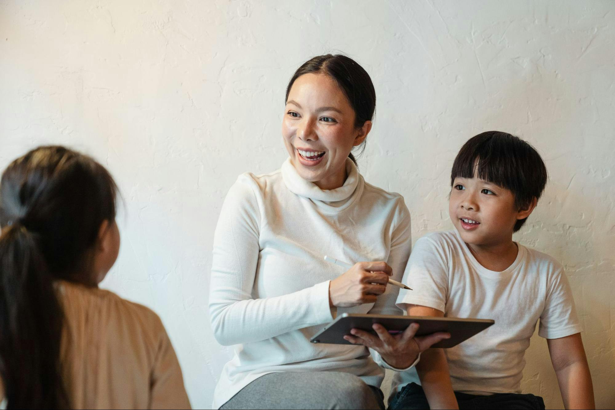 A mother and her two children use a learning app on a tablet.