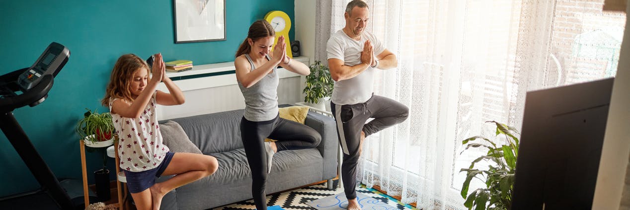 Father and his two daughters practicing yoga with online classes.