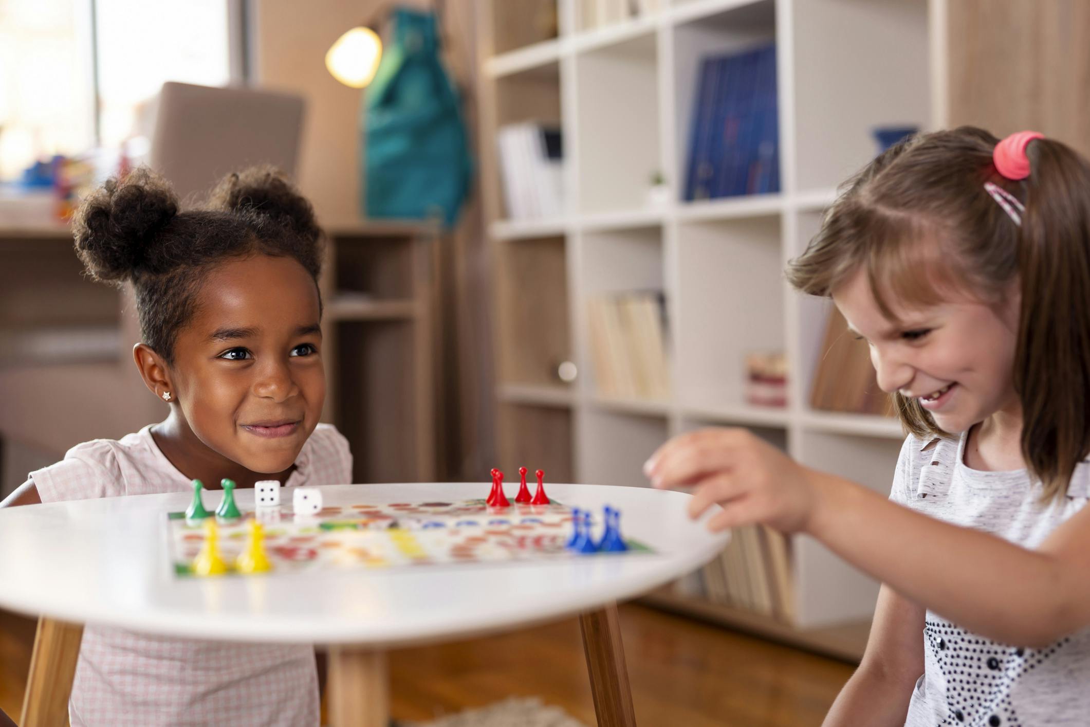 Two young girls playing a board game at home.