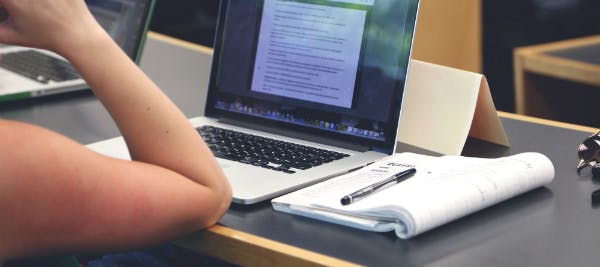 A laptop and notepad on a desk.