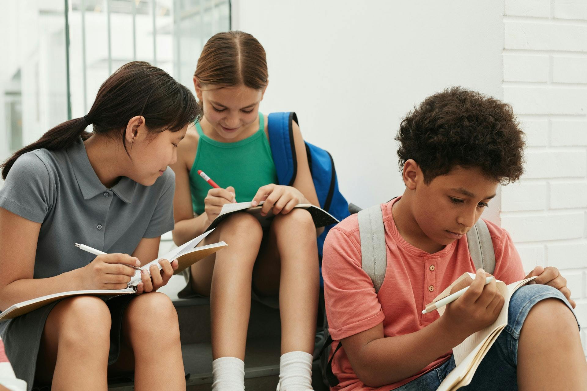 Three students complete fun writing activities at school. 