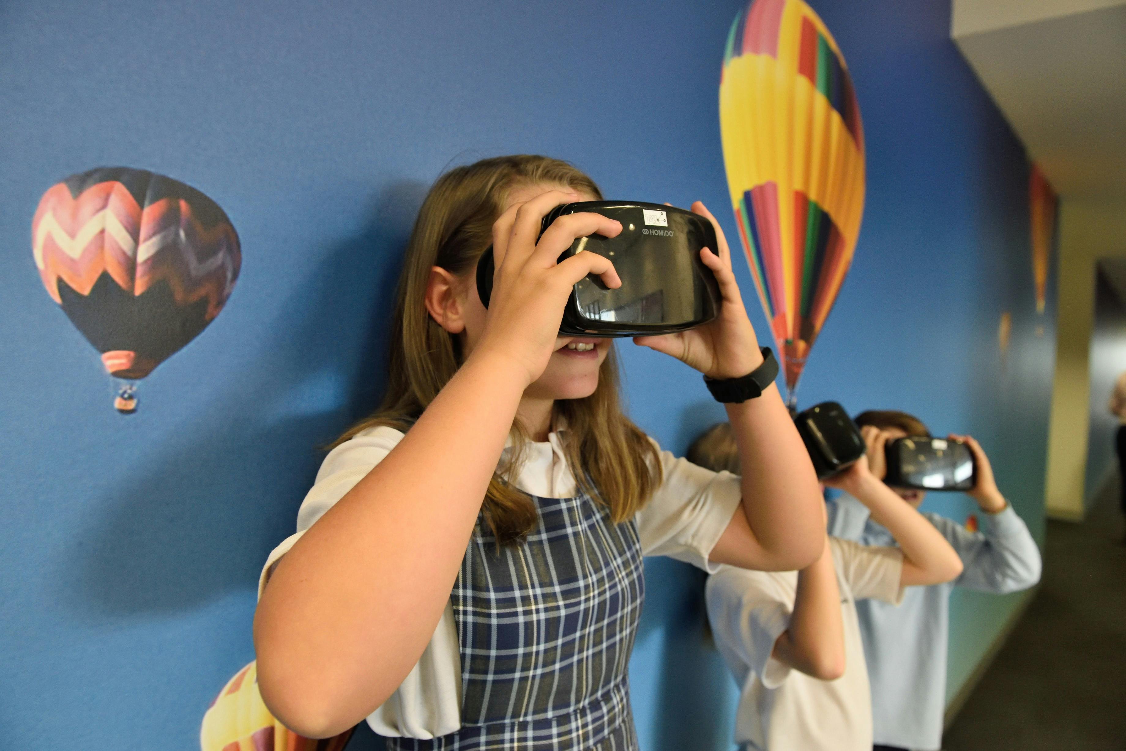 Three students use virtual reality headsets as part of a type of game-based learning activity.