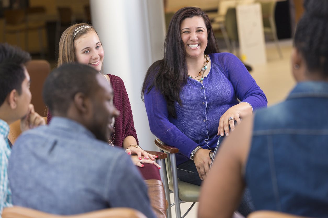 Parent and her daughter smiling in a support group circle for families