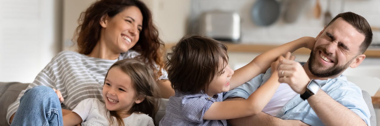 A family of two parents and two kids sitting on the couch and setting family goals together. 