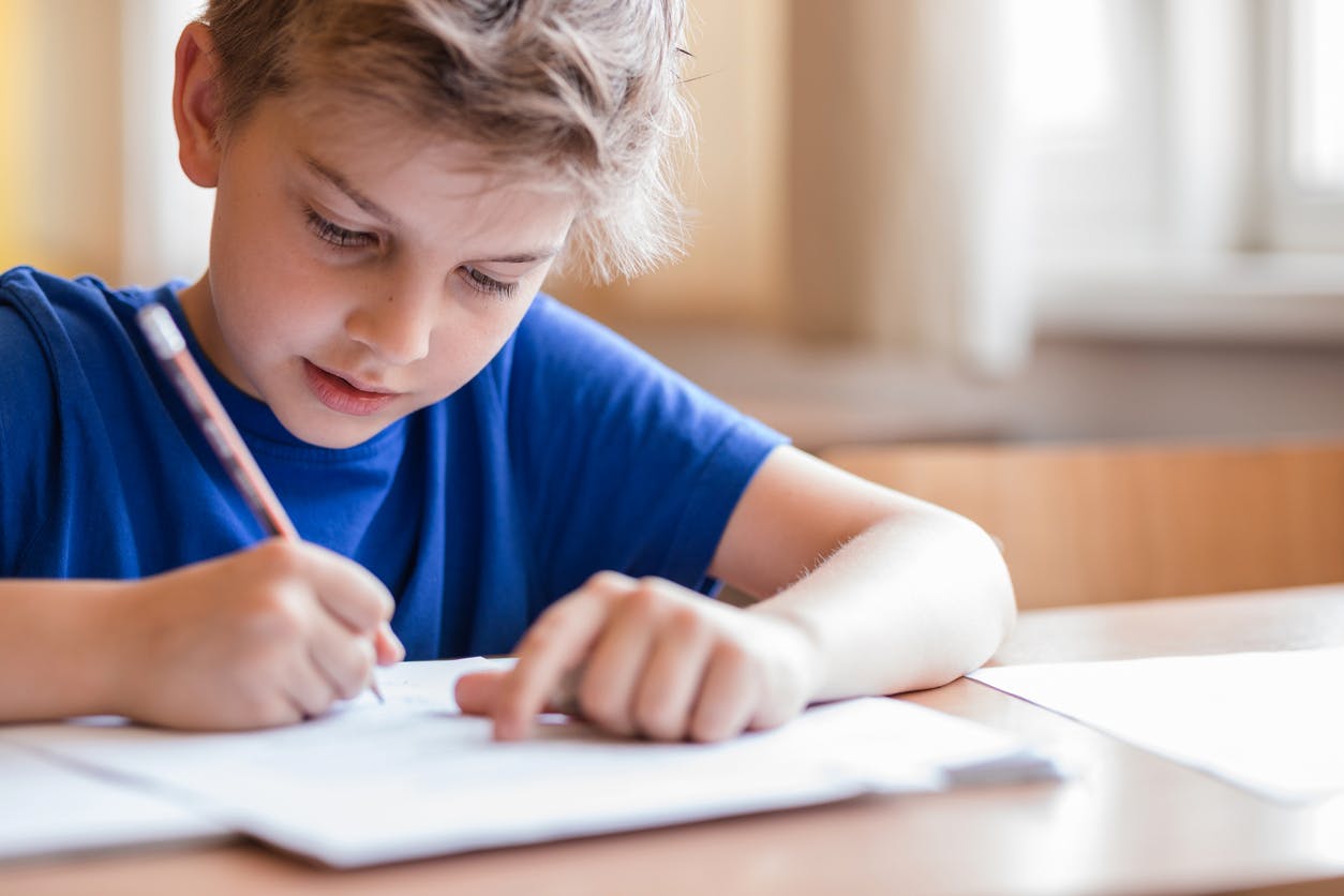 Child confidently working in a notebook at his desk after expanding his math knowledge through a math intervention program. 