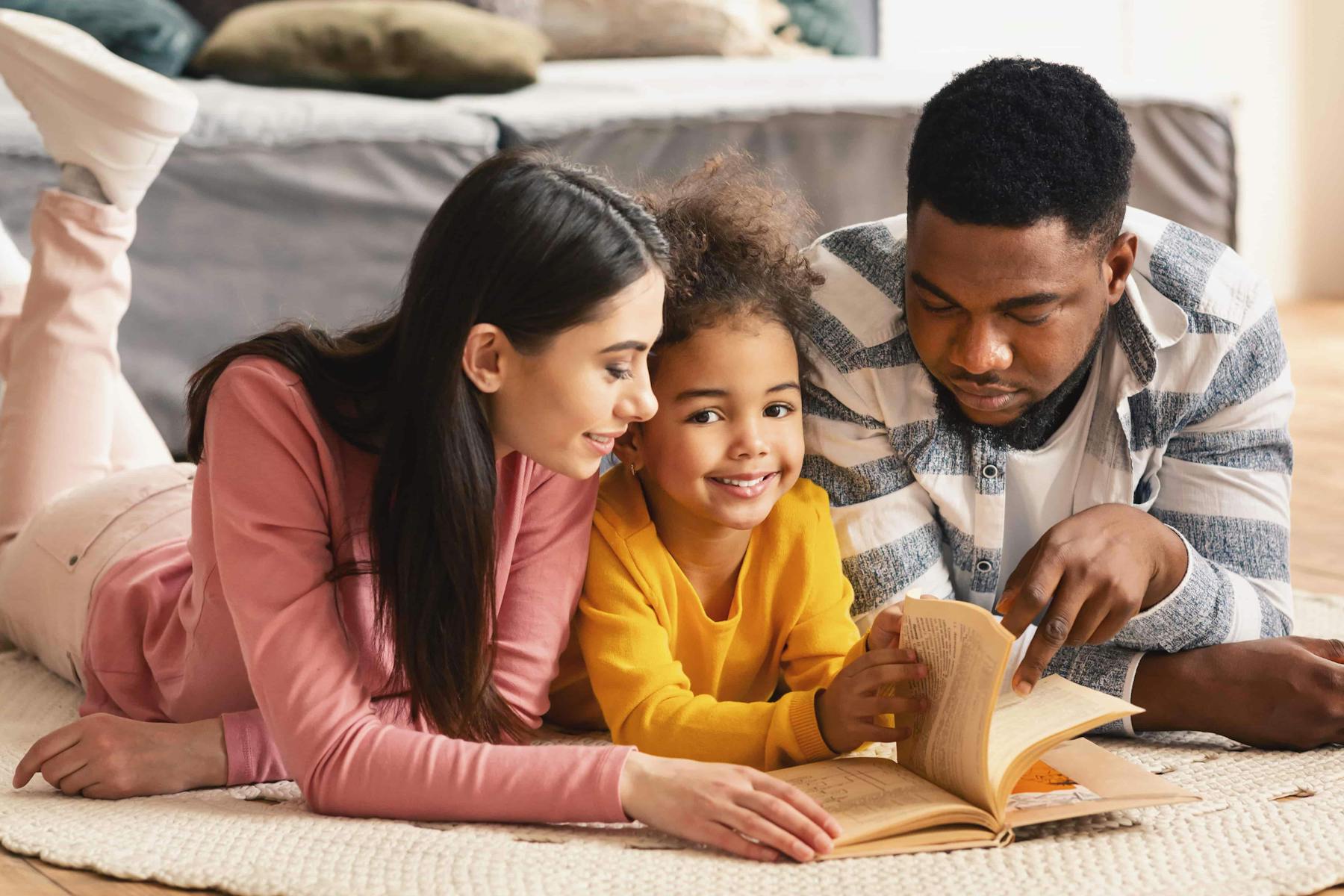 Parents reading with child on floor.
