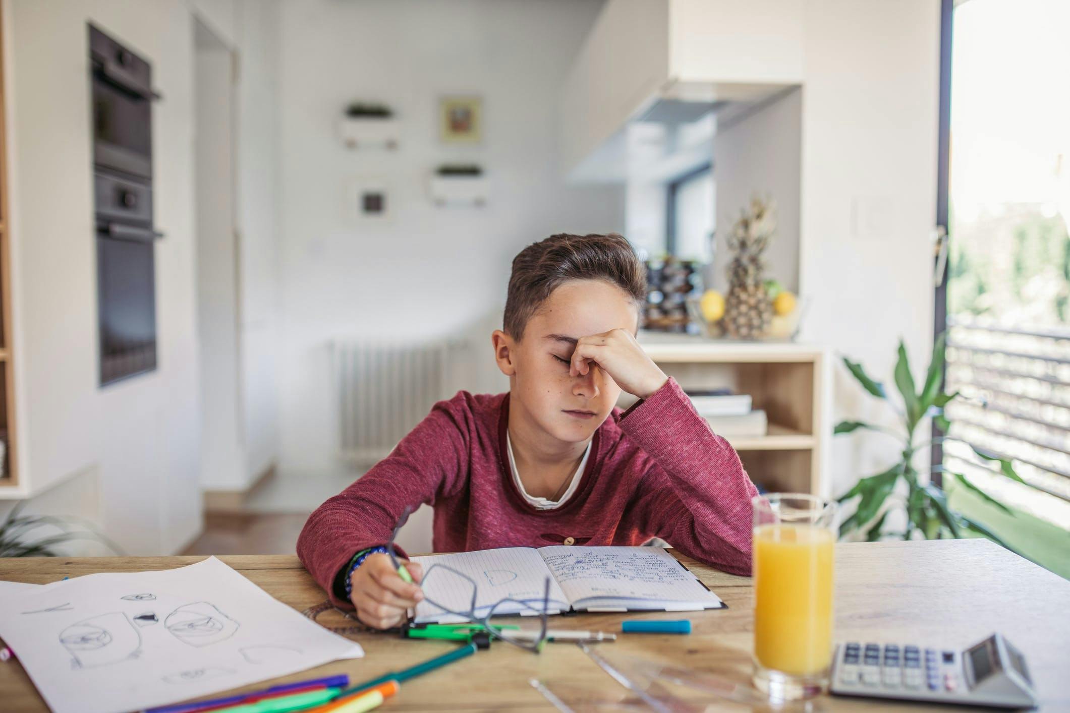 Frustrated child struggling with math homework at his desk.