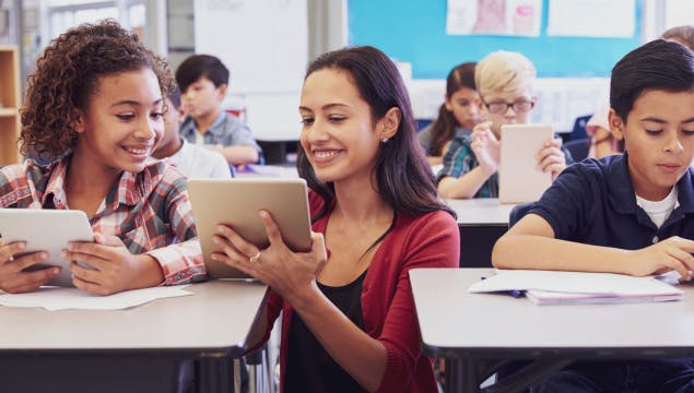 Teacher showing student game on tablet in classrom