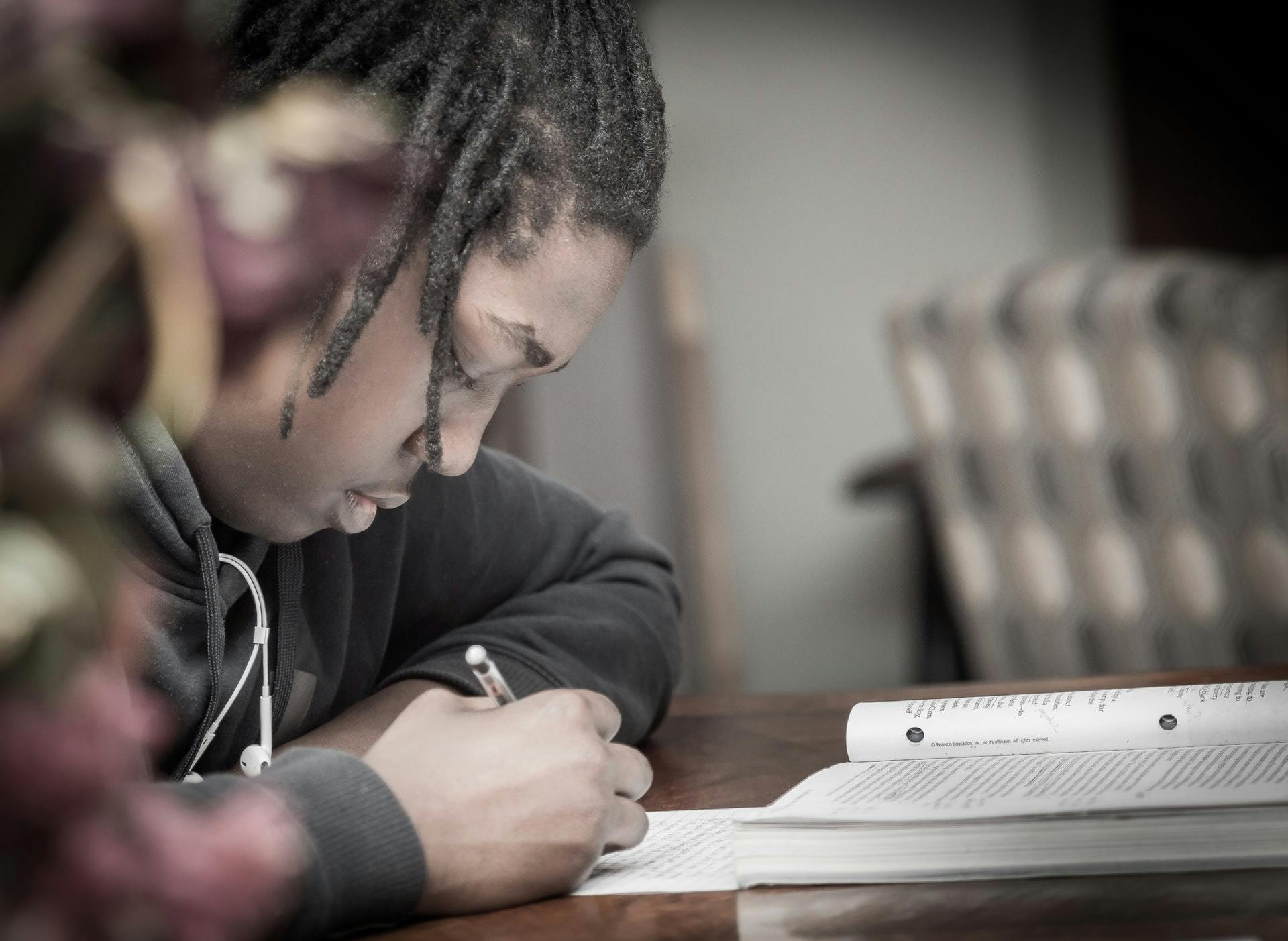 Students works with a textbook, pencil and paper in the classroom. 