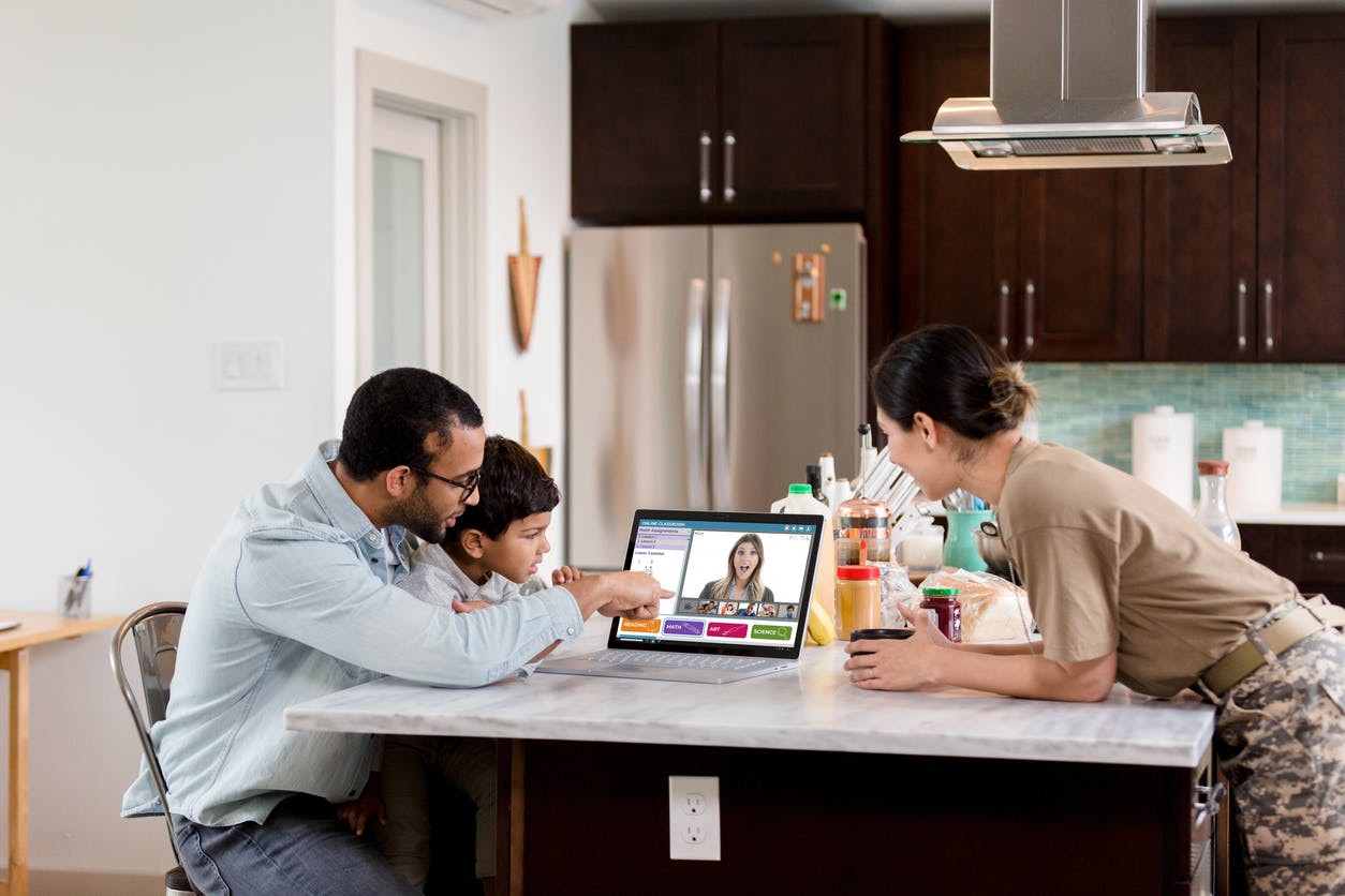 A preschool age boy and his parents watch the boy's preschool teacher during a live stream preschool class. The boy is distance learning during the COVID-19 pandemic.