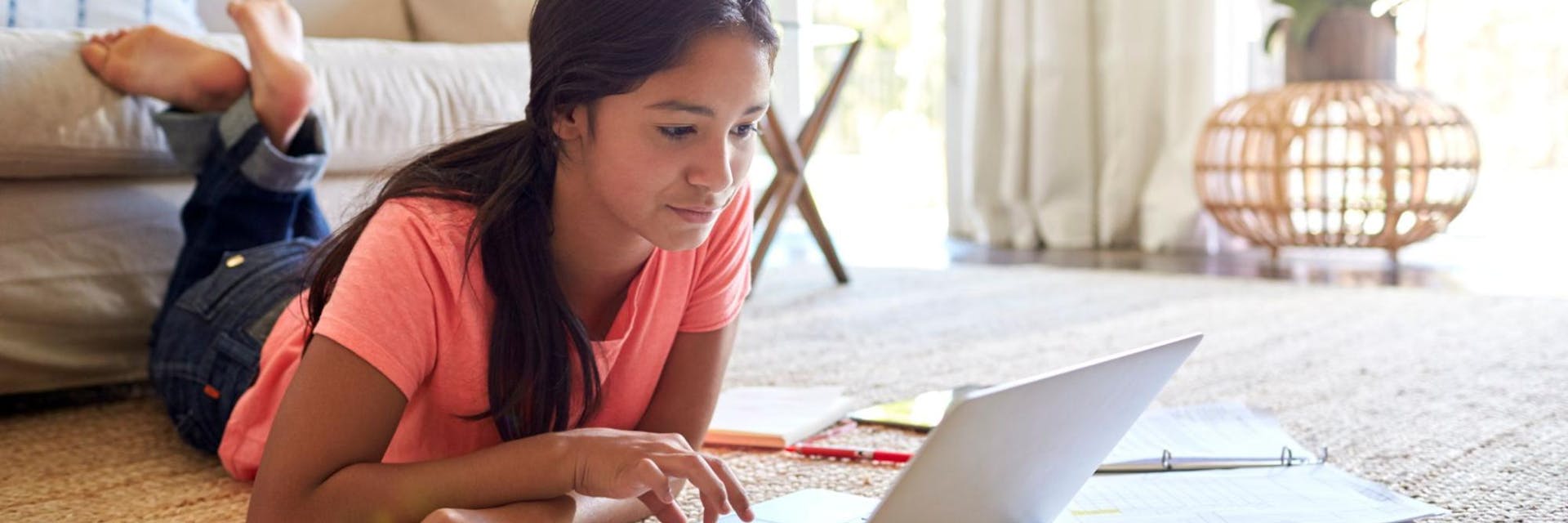 A student laying on the floor of her living room uses study strategies to prepare for her next test.