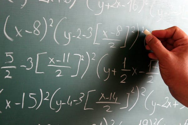 A hand is calculating math problem on a blacboard