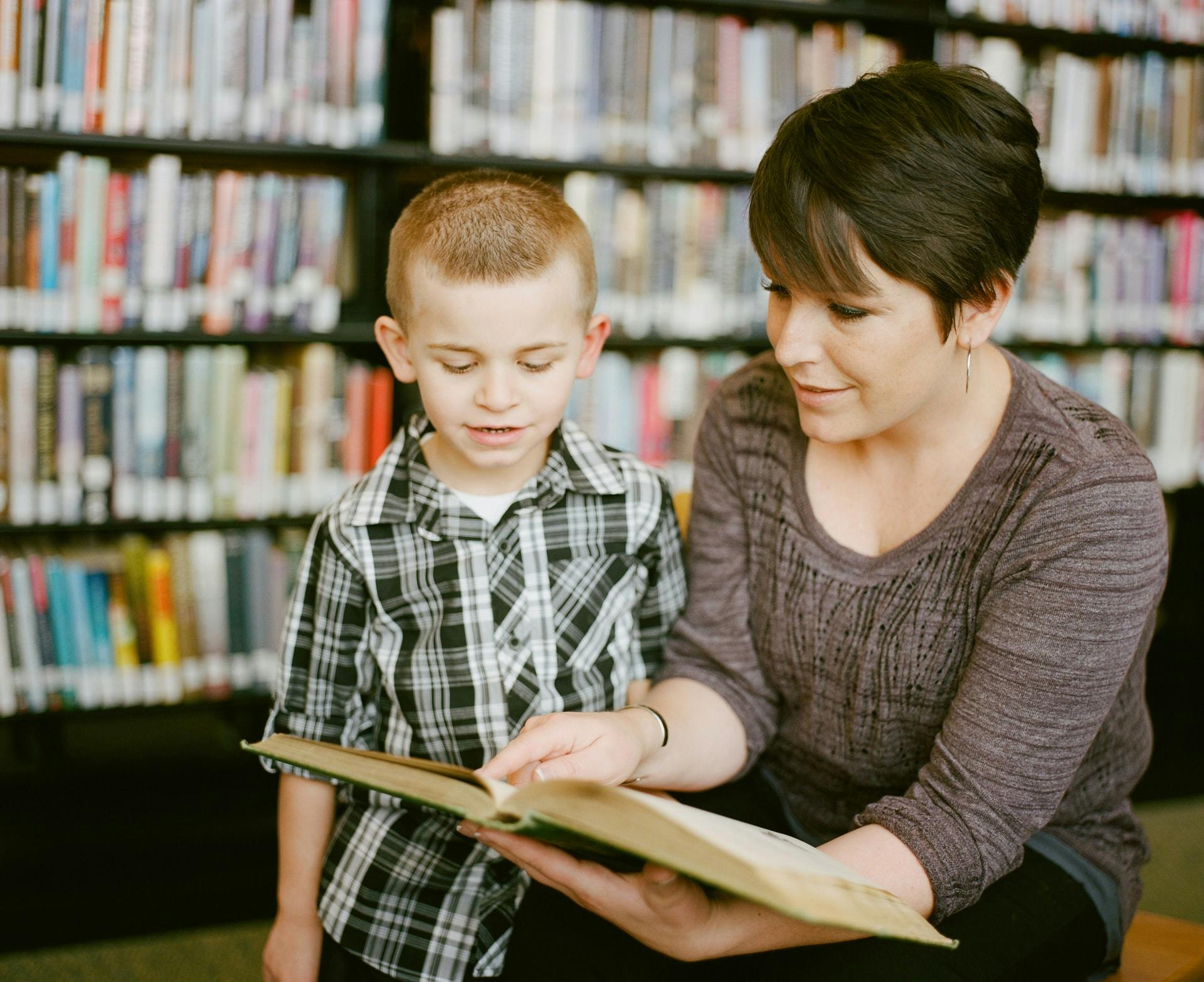 A teacher and student read a book together as part of a personalized learning plan.