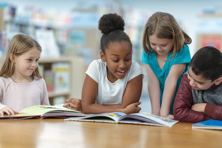 Four students reading a variety of books in class.