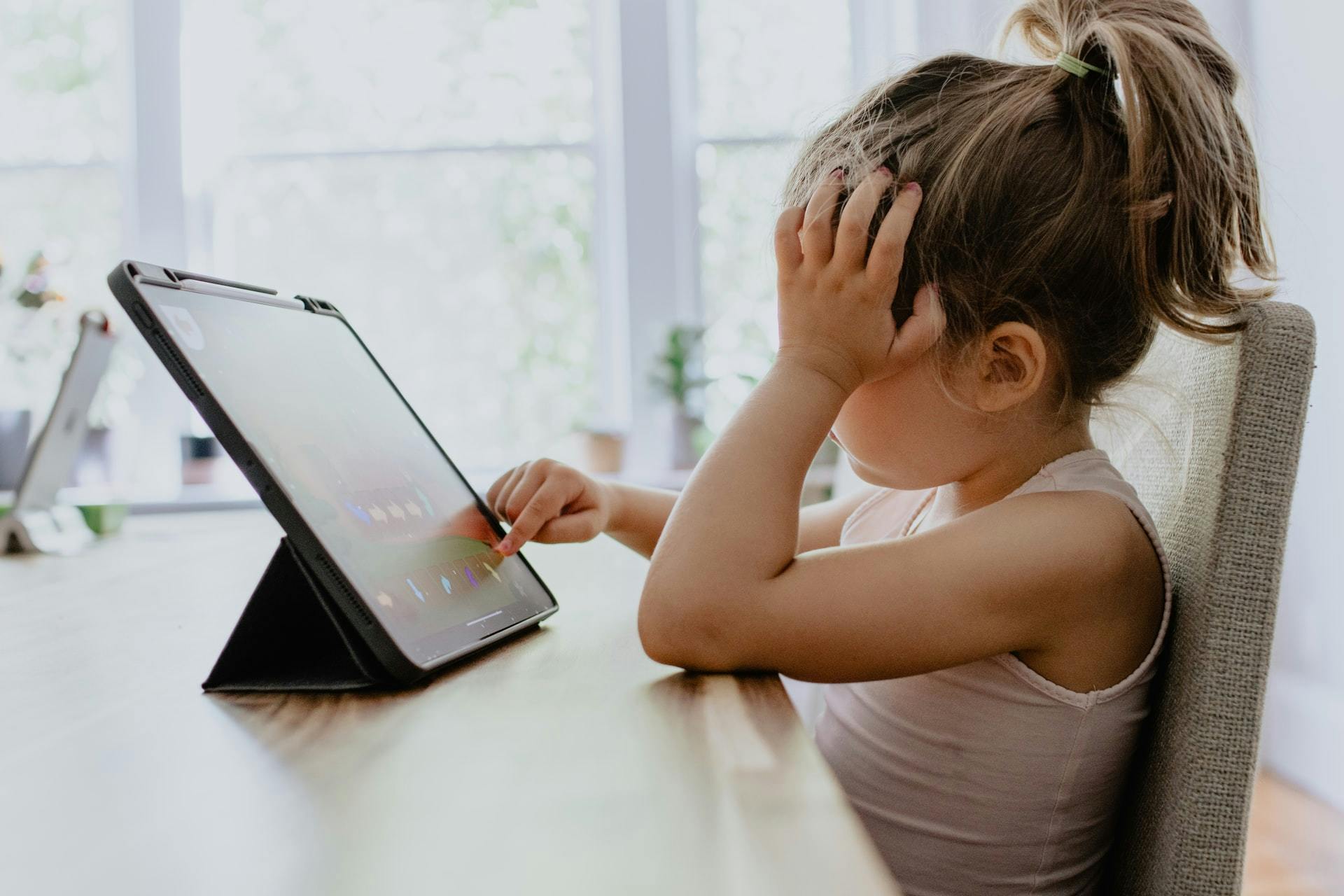 Young girl uses a tabled while completing a virtual learning assignment.