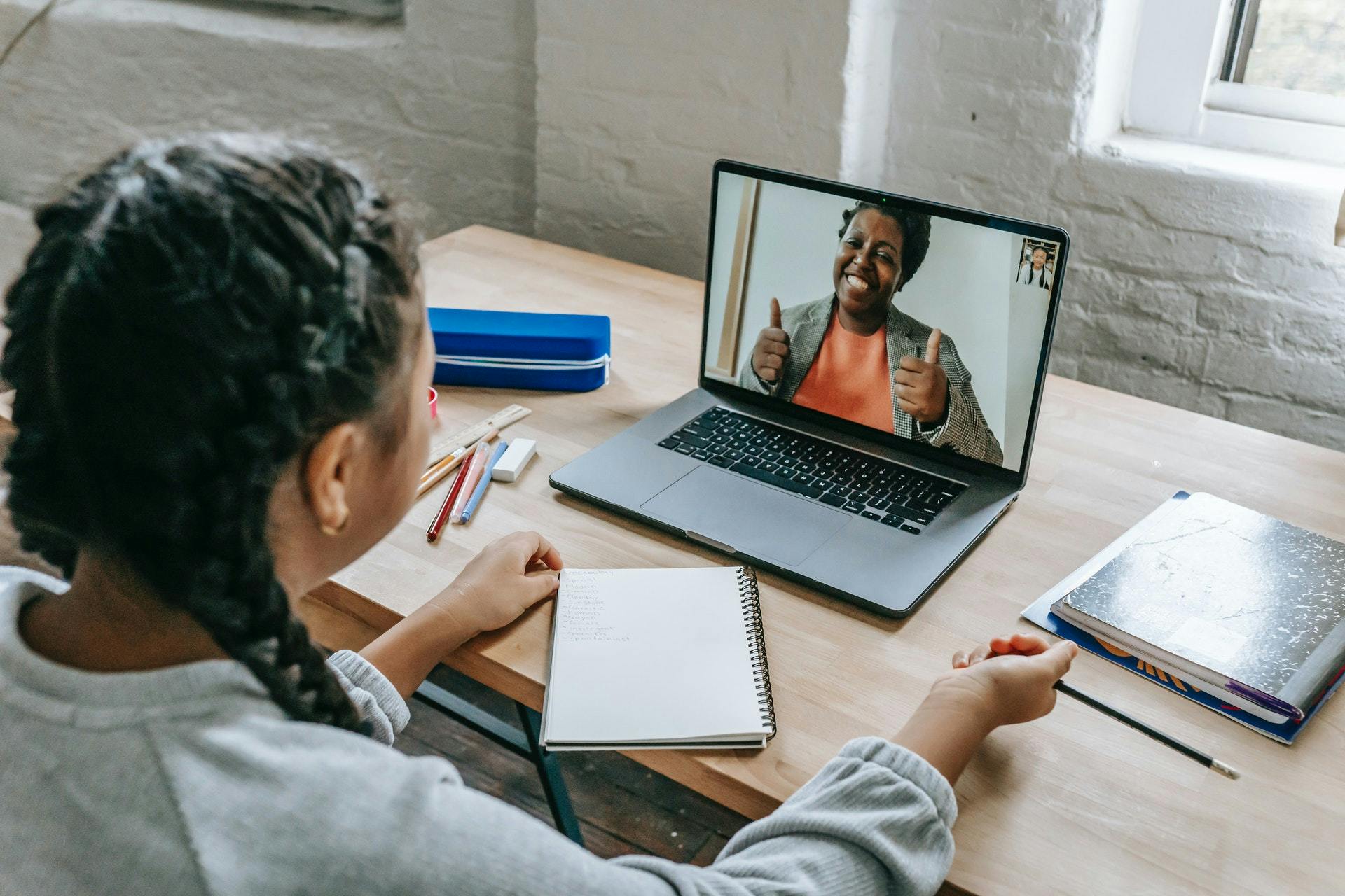 A student uses remote learning tools to connect with her teacher on a laptop at home.