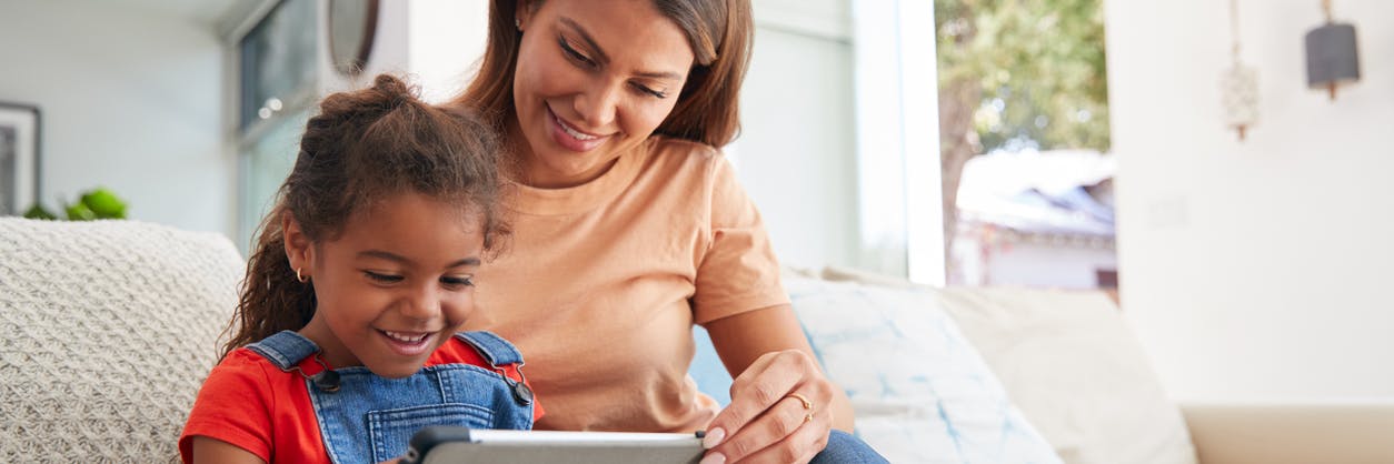 Parent and her daughter looking at educational resources on a tablet together 