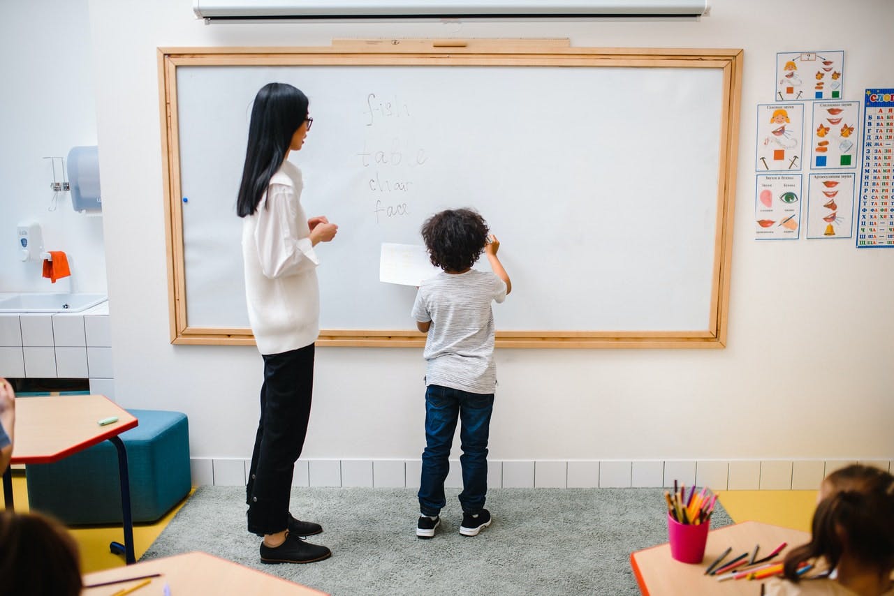 Student and teacher stand at the whiteboard while doing English games. 