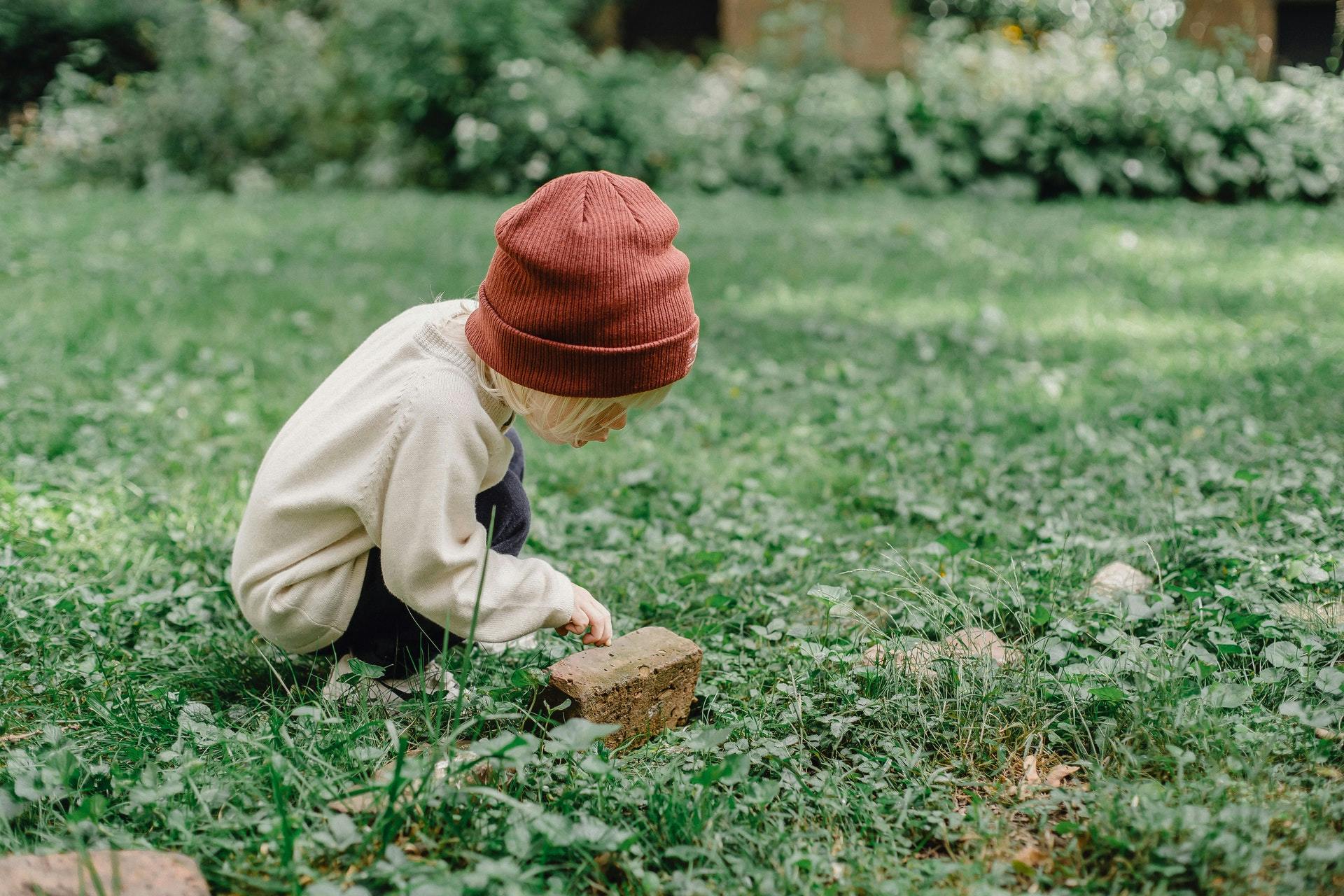 A young boy investigates a rock during some earth day activities for kids. 
