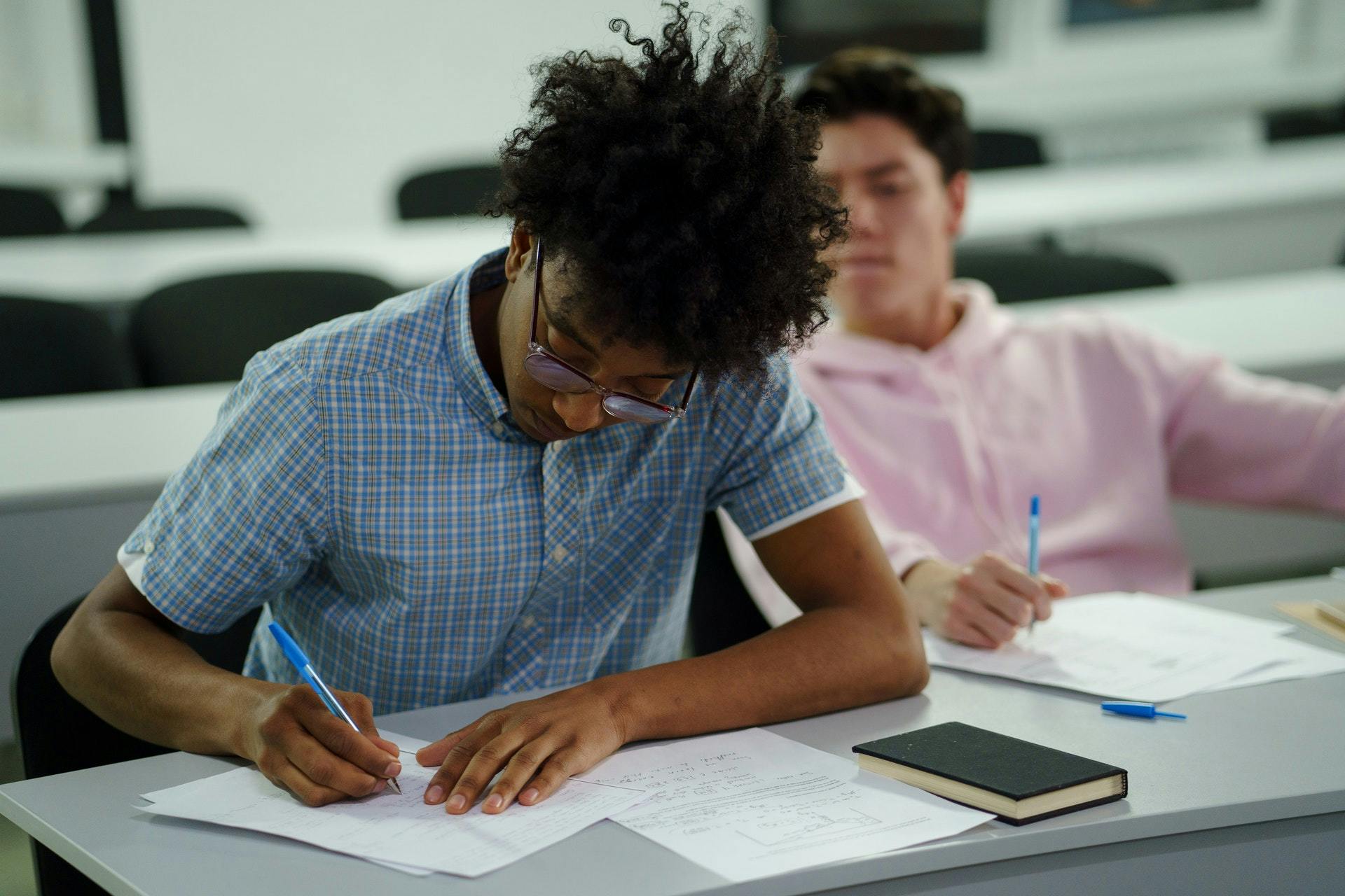 Two students write a practice test together in a classroom. 