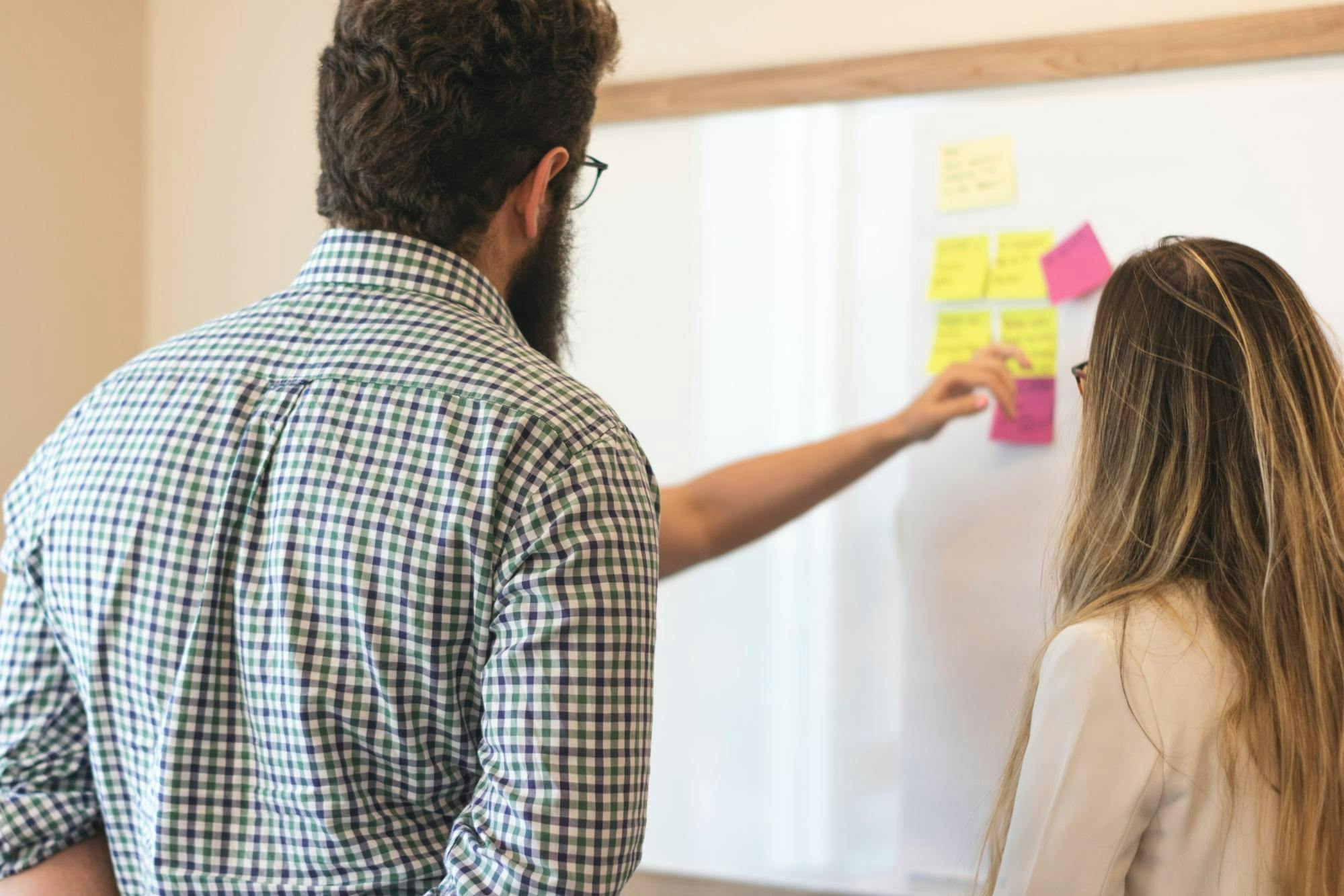 Teachers stand in front of a whiteboard with colorful post-it notes and plan social emotional learning activities