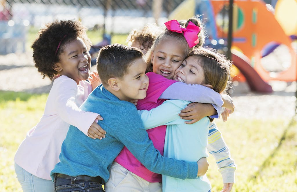 Kindergarten students hugging each other on the playground