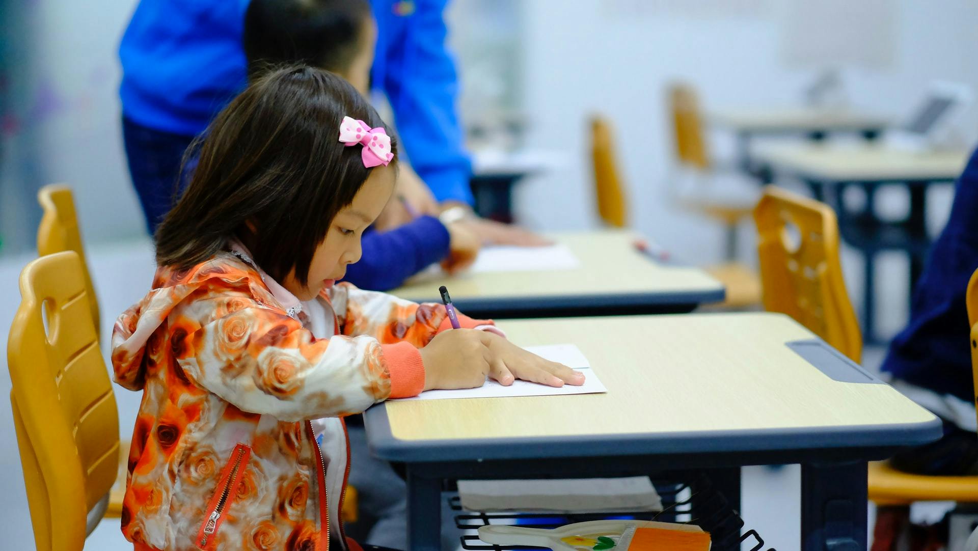 A young student sits at her desk and works on a reading comprehension activitiy.