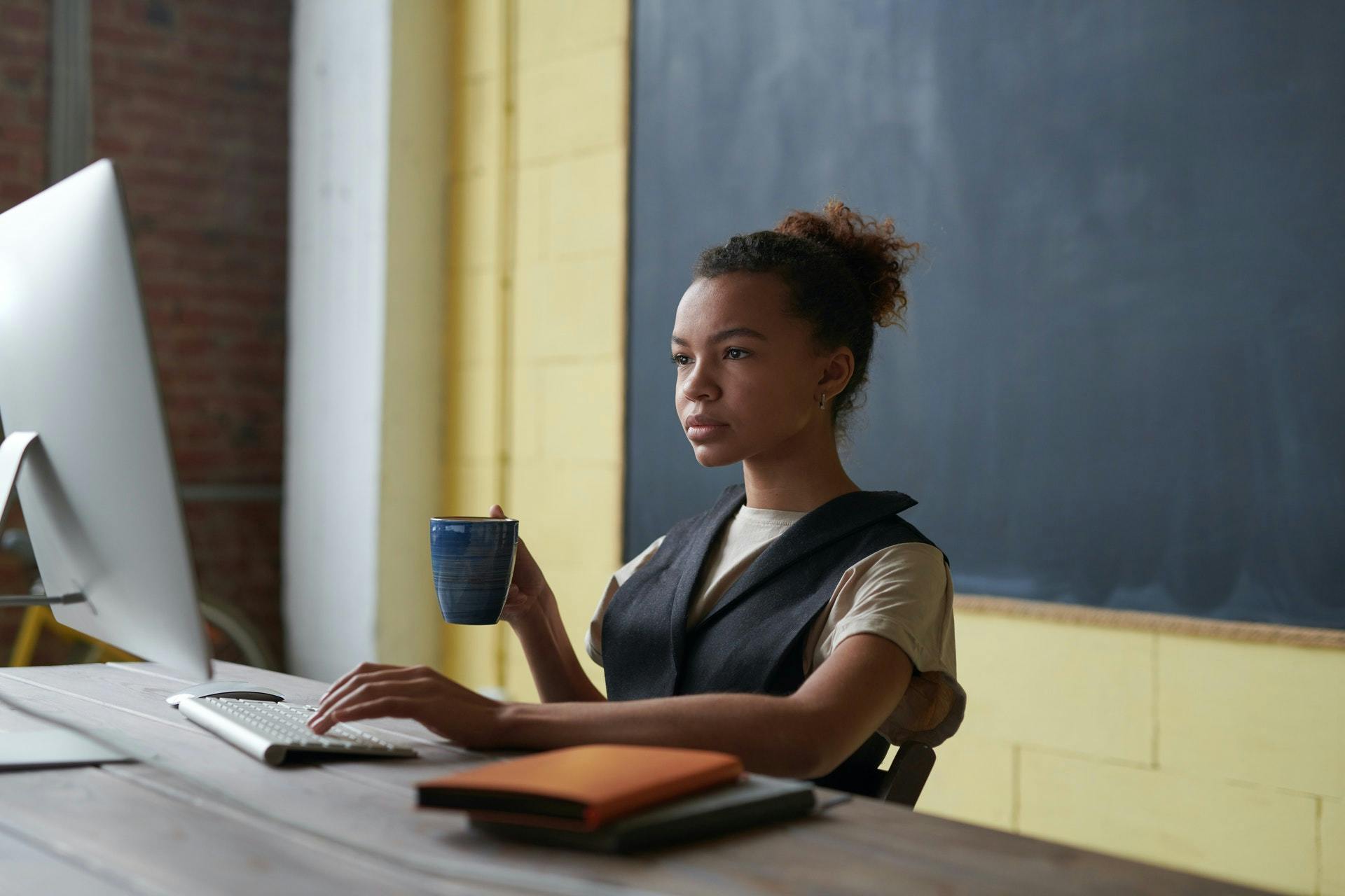 A teacher sits at a computer in her classroom and uses online learning tools.