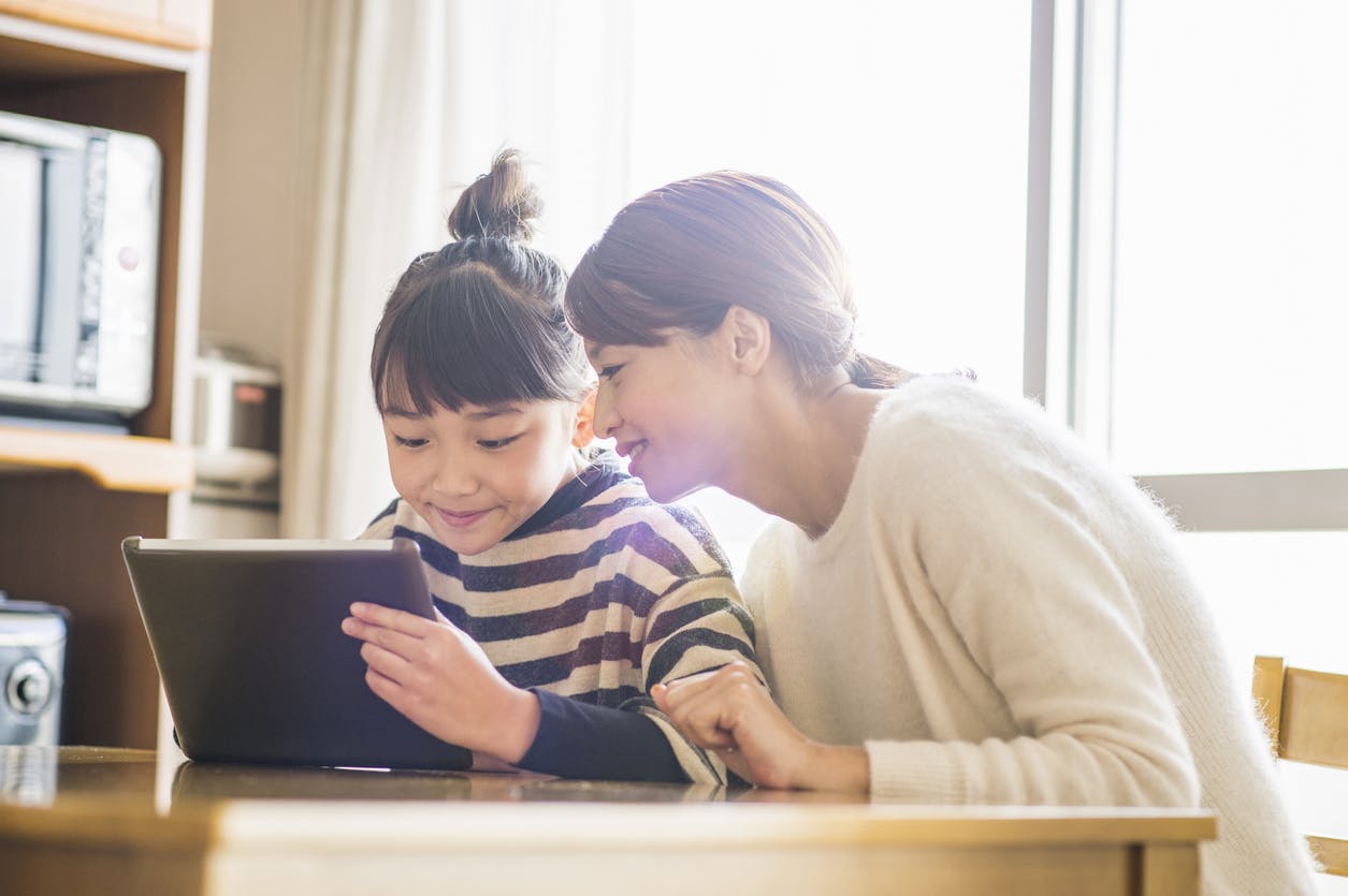 A mother sitting with child learning on a tablet