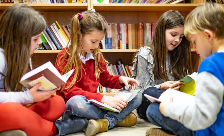 Four students reading books in their classroom library.