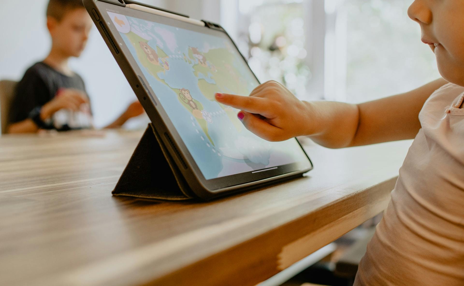 Young student uses a learning app on a tablet while sitting at a table. 