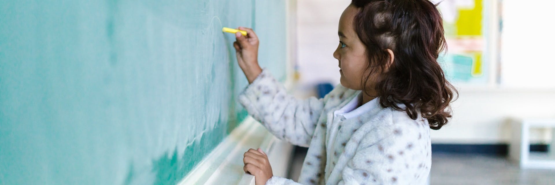 Young girl stands at a chalkboard and works on subtraction activities.
