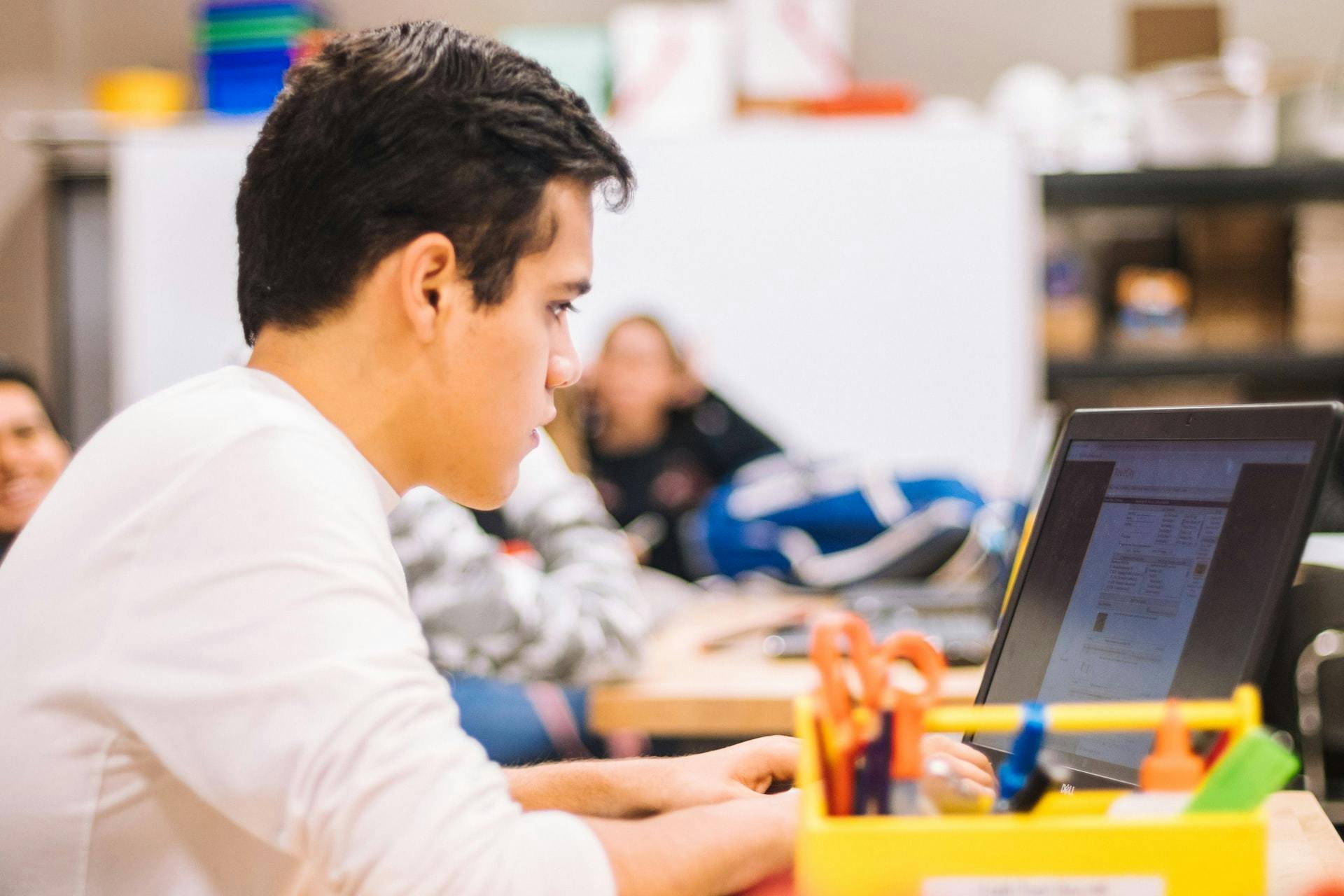 A male student works on a computer in the classroom after returning to in-person learning.