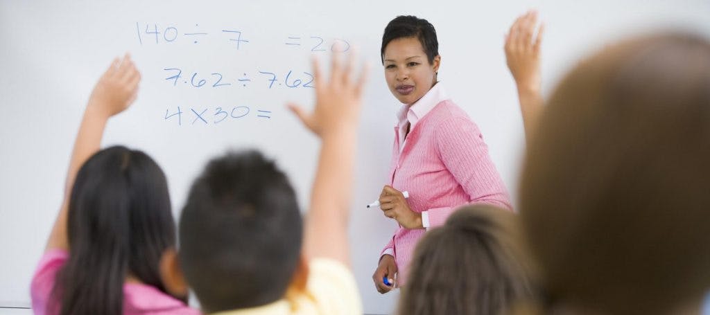 Teacher asking students a question on a whiteboard.