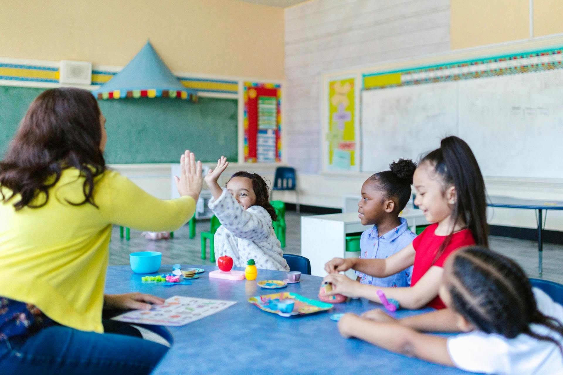 A teacher and student high five during an English game.