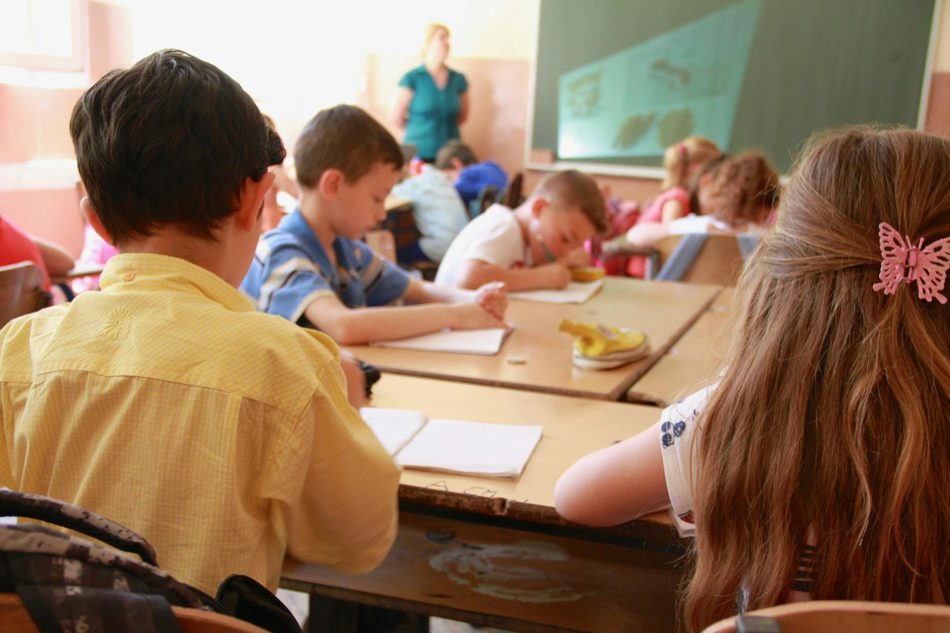 Elementary students doing work at a group of desks.