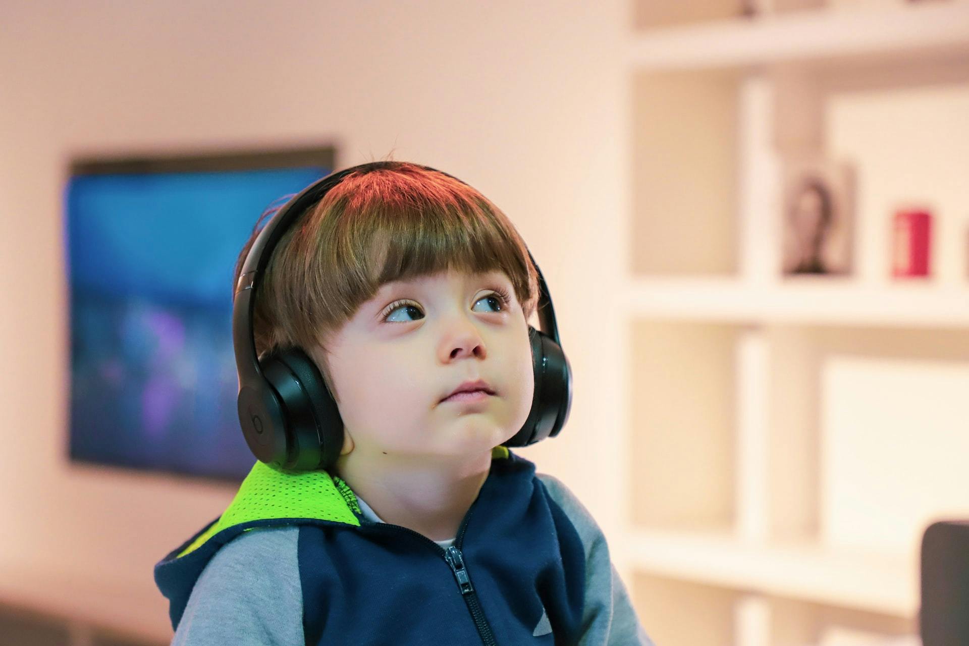 Young boy listens to over ear headphones during alternate ELL activities.