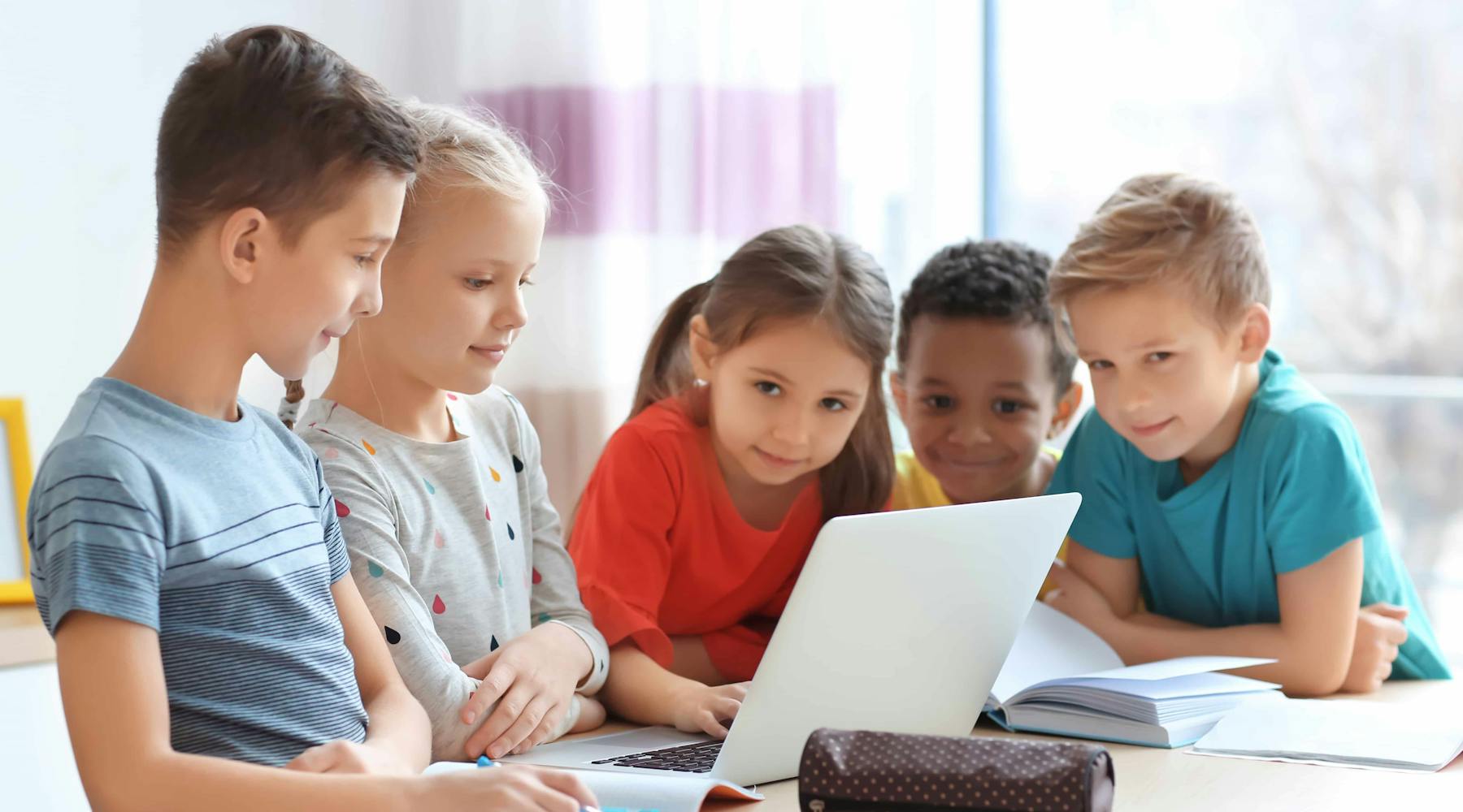 A group of kids using a computer for gameschooling.