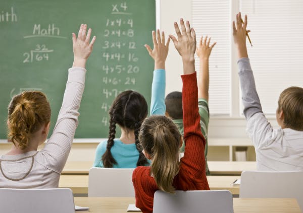 learning activities mathematics A classroom of young students with their hands raised to answer.