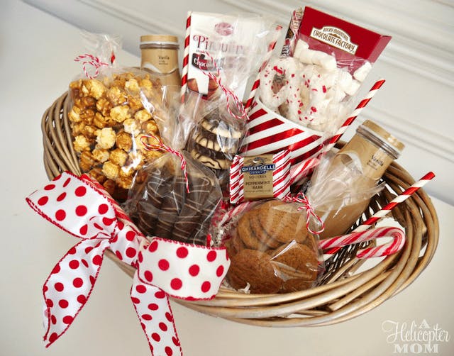 DIY wicker gift basket with a white and red polka-dotted ribbon and filled with holiday treats.