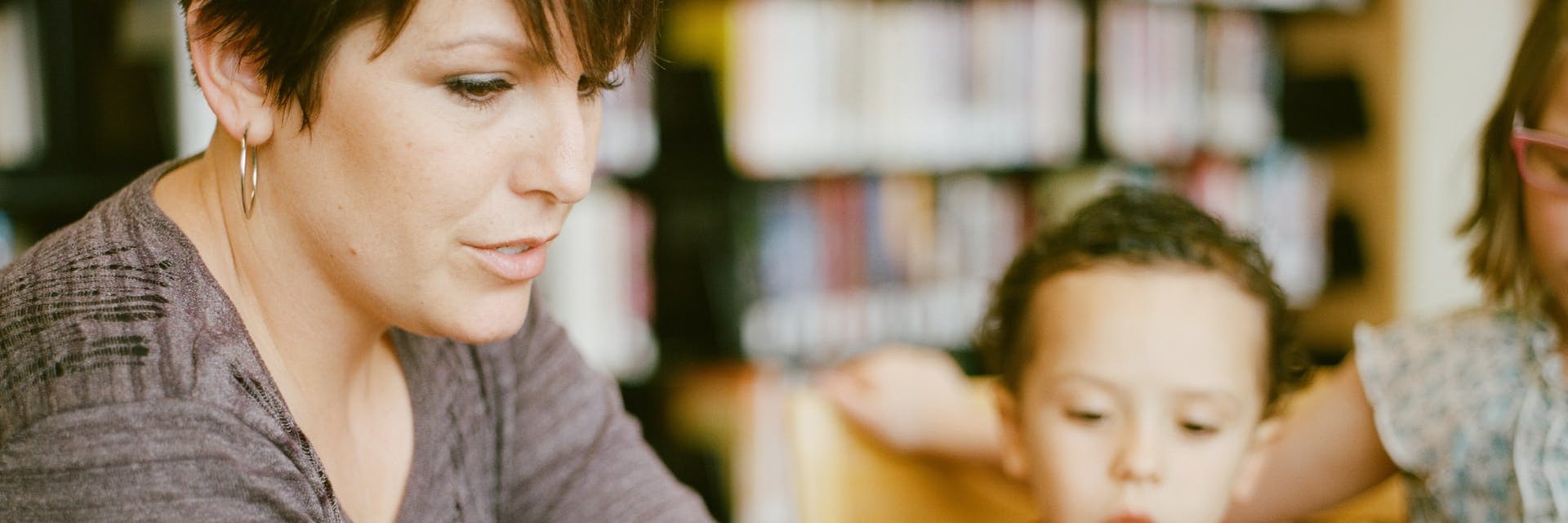 A teacher reading to a couple of their students.