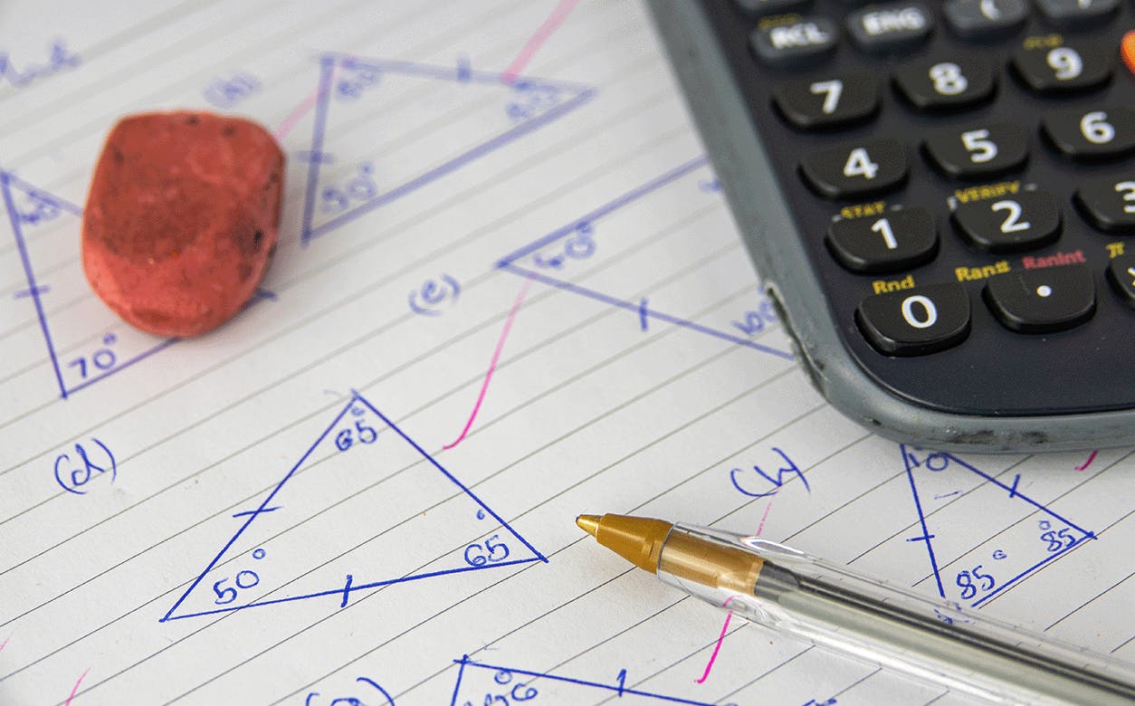 A calculator, a pen, and a red rubber placed on a piece of paper