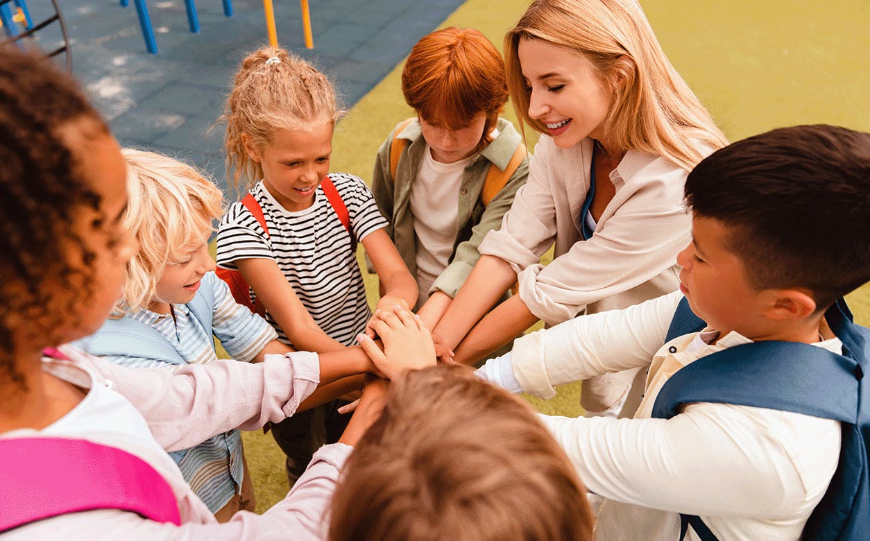 A teacher surrounded by children, all holding hands