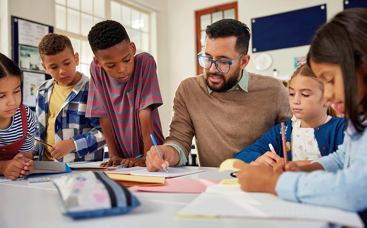 A teacher assists students with their homework, providing guidance and support in a classroom setting.