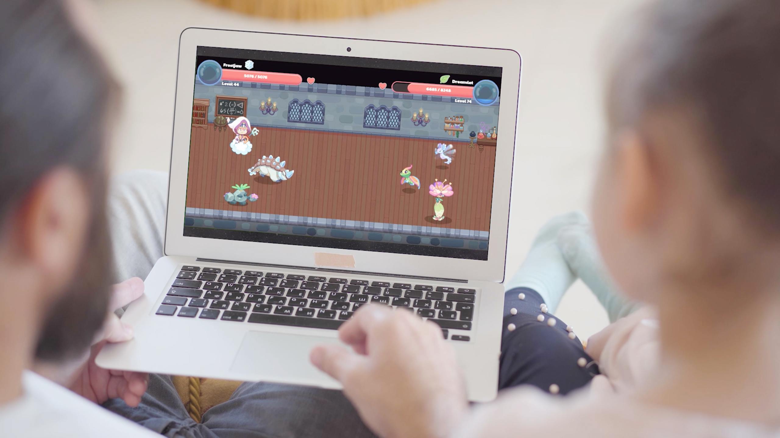 Father and daughter sitting on couch, bonding over the Prodigy English game on computer