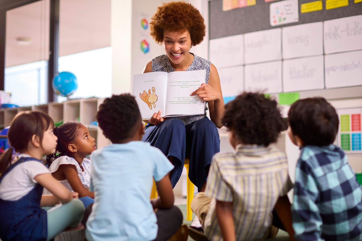 A teacher reading a book to a group of attentive children in a classroom