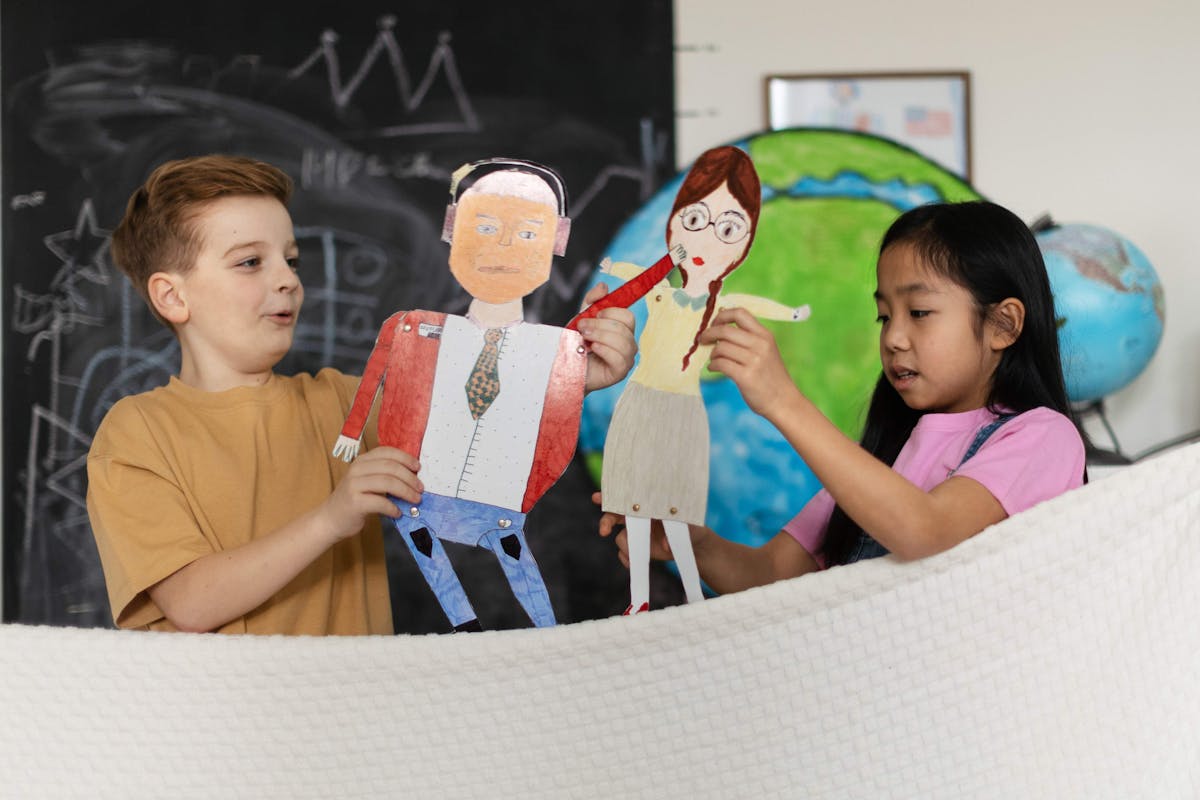 Kids with paper cutouts in hand, standing near a blackboard, enjoying a fun craft project