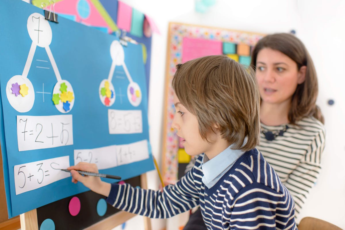 A student and a teacher solving a math problem on a board